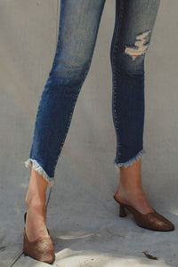 Cotton blend medium wash stretch high rise ankle skinny with fray bottom detail. Subtle distressing on knee area.