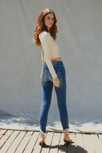 Cotton blend medium wash stretch high rise ankle skinny with fray bottom detail. Subtle distressing on knee area.