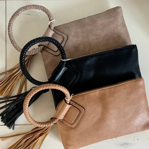 Vegan leather clutch with woven ring handle and tassel detail.  Interior zipper & 6 card storage slots.  Clutch (body) measures approx 10" x 6.5". Colors: Black, Stone, Camel.