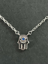 Load image into Gallery viewer, White gold dipped dainty necklace with Hamsa charm and small sapphire colored CZ in center. 
